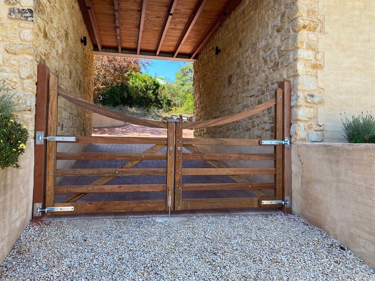 A recently completed custom timber gate set in a stone entrance