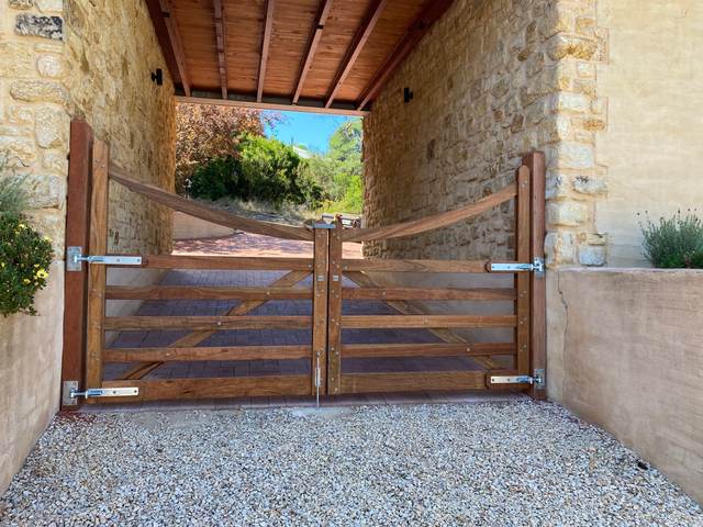 Welsh-style curved-top entrance gates in spotted gum, hung as a pair in a stone entrance