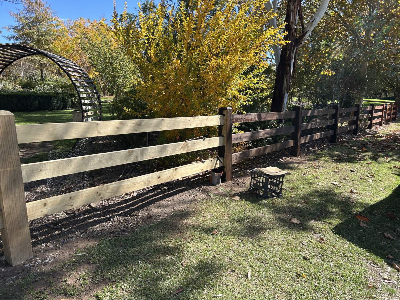 Post and rail with a dark top rail along a garden