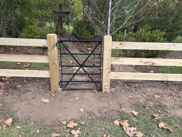 Steel garden gate set into a post and rail fence
