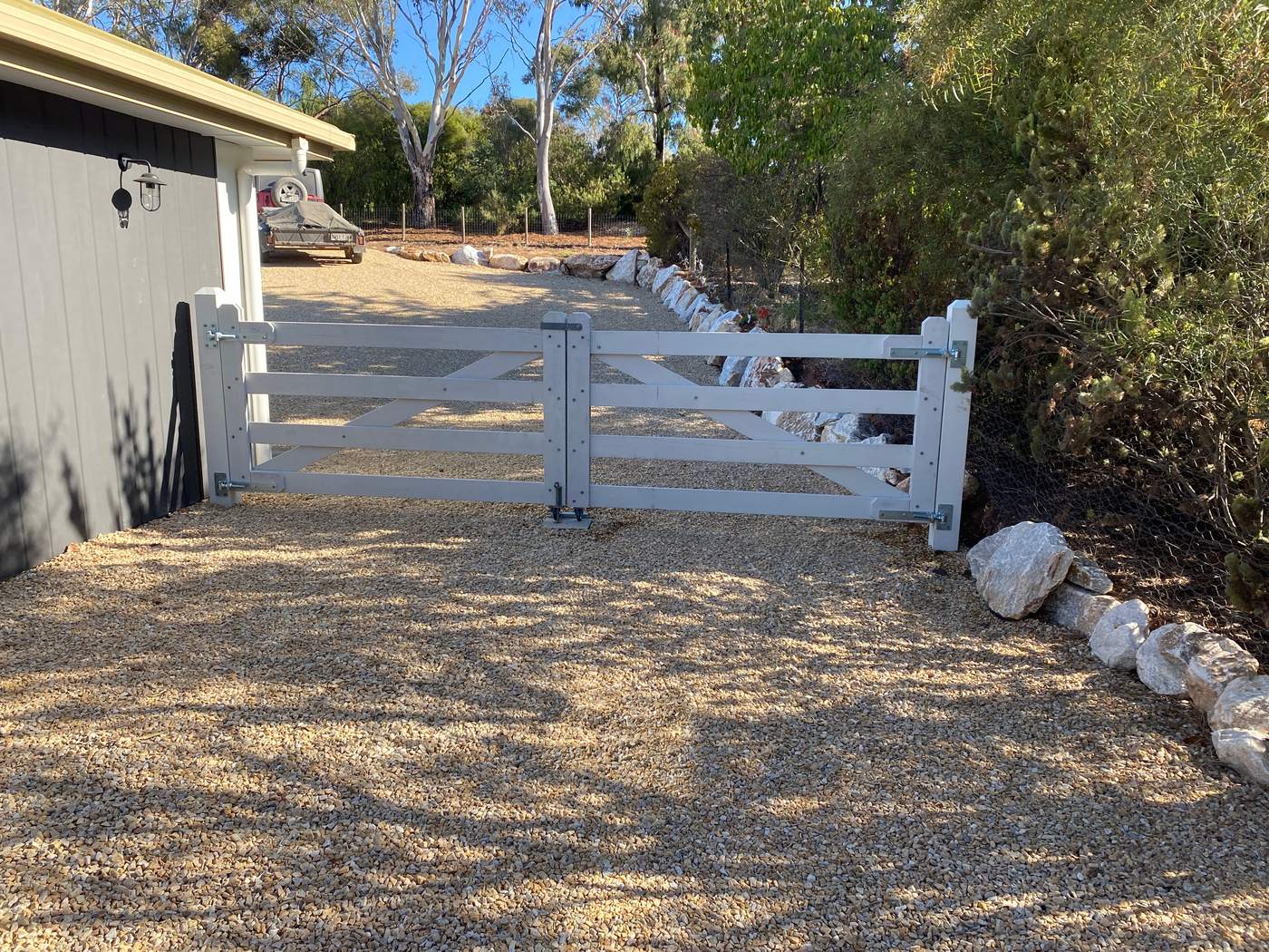 Painted white double gates on a gravel drive